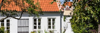 Ældre hyggeligt hvidt hus med blomster og græsplæne
