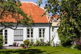 Ældre hyggeligt hvidt hus med blomster og græsplæne