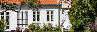 Ældre hyggeligt hvidt hus med blomster og græsplæne
