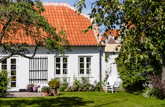 Ældre hyggeligt hvidt hus med blomster og græsplæne
