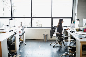 Kvinde Sidder Ved Pc På Kontor Foran Et Stort Vindue