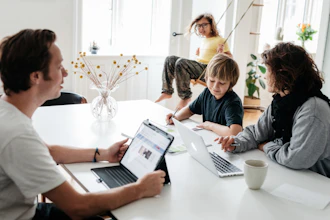 Familie Sidder Omrking Bordet I Stuen Med Bærbar Pc Pige På Gynge I Baggrunden