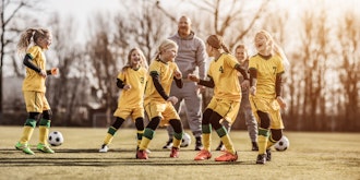 Fodboldhold med piger og deres træner spiller fodbold