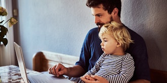 Mand Sidder Med Et Lille Barn Og Kigger På En Bærbar Pc