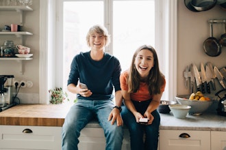 Ung Mand Og Kvinde Sidder På Køkkenbordet Med Mobiltelefoner