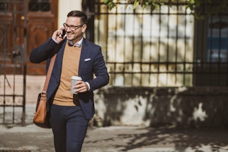 Mand Taler I Mobiltelefon Med En Kop Kaffe I Hånden