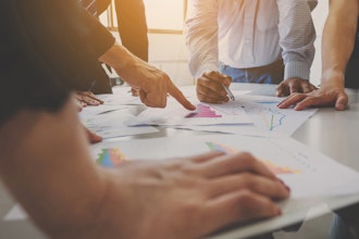 En Grupper Personer Står Omkring Bord Og Peger På Papirer Med Grafer