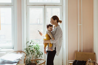 Kvinde Holder Lille Barn På Armen Og Taler I Mobiltelefon