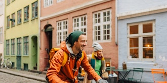 Mand Og Kvinde På Cykel På En Brostensvej Med Gamle Huse