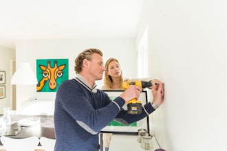 Mand Borer I Væg Og Kvinde Holder Billede Der Skal Hænges Op