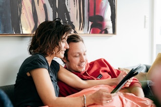 Kvinde Og Mand Sidder I Sofa Og Kikker På Ipad