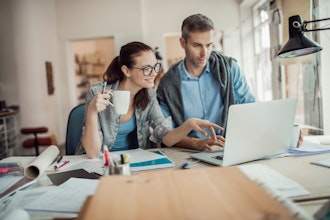Kvinde Med Kaffekop Sidder Sammen Med Mand Foran Pc