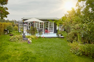 Baby På Græsset Foran Kolonihavehus