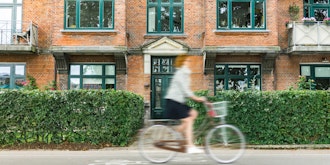 Kvinde Cykler Forbi Facade Med Lejligheder