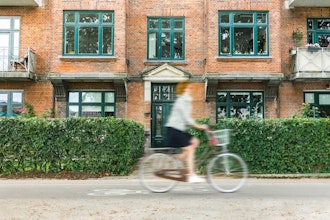 Kvinde Cykler Forbi Facade Med Lejligheder