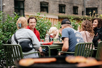 En Gruppe Sidder Og Spiser I En Baggård