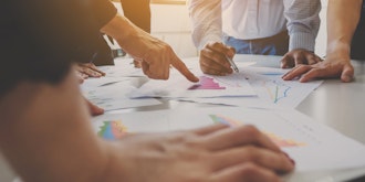 En Gruppe Står Omkring Et Bord Og Kikker Papirer Med Grafer