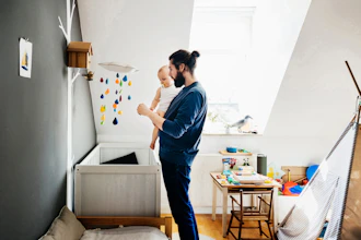 Far Holder Lille Barn På Armen Ved Sengen