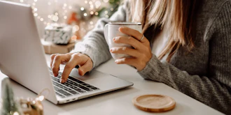 Kvinde Sidder Med En Kop Kaffe Ved Bærbar Pc Og Julegaver Bagved