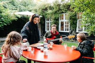 Familie Hygger Sig Ved Rødt Havebord I Haven