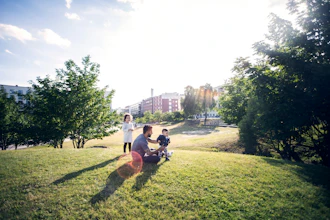 Far Sidder På Græsset Og Leger Med Sine To Børn